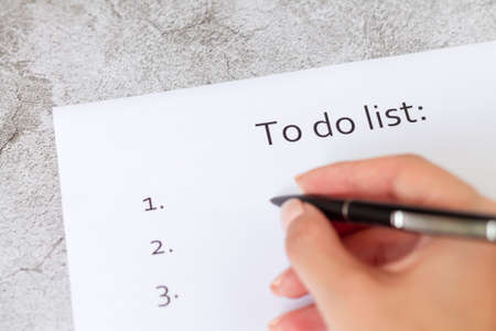 Hand writing business plan, strategy or goals. To do list on blank paper page on light gray stone background close-upの写真素材