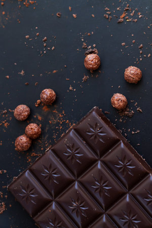 Delicious dark chocolate bar with shavings, crumbs, rice balls top view on slate tableの写真素材