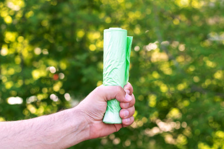 Man holding eco plastic green garbage bio bag in roll outdoors