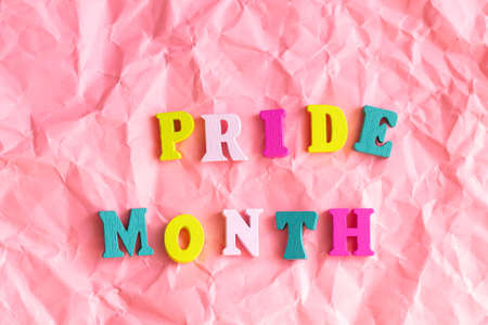 Text "Pride Month" with rainbow wooden letters top view on pink background, LGBTQ + party decorの写真素材