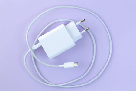 Mobilephone charger for fast charge through USB cable on purple background top view