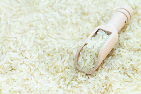 Wooden scoop of raw white organic rice, ingredient for cooking asian foodの写真素材