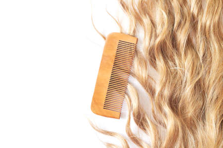 Beautiful wavy blond hair with bamboo comb isolated on white background top view. Haircare and hairstyle conceptの写真素材
