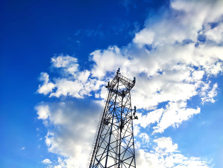 Telecommunication tower antenna at blue cloudy sky