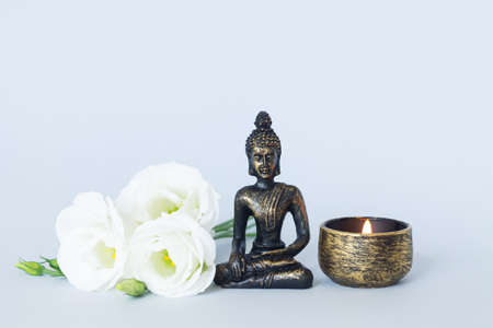 Buddha statue on altar with candle and flowers. Meditation, buddhism and enlightenment conceptの写真素材