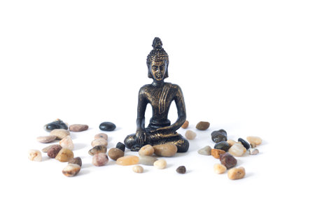 Meditating Buddha statue with pebbles isolated on white background. Zen garden or meditation place conceptの写真素材