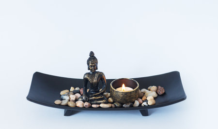 Altar with Buddha statue, burning candle and pebbles. Meditation, buddhism and enlightenment conceptの写真素材