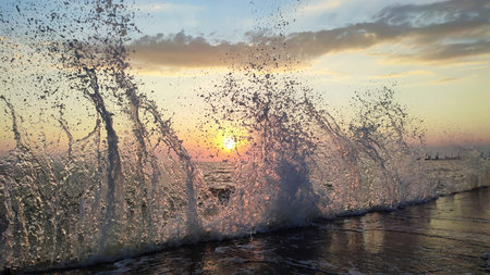 Splashing high wave on sea coast at sunset. Beautiful nature backgroundの写真素材