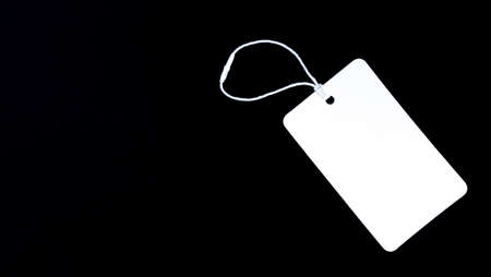 One blank white paper cloth label or price tag on black background. Black Friday conceptの写真素材