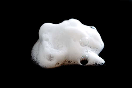White foam with bubbles from soap, cleanser or shampoo isolated on black background close-upの写真素材