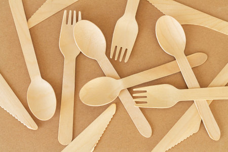 Set of disposable wooden spoons, knives and forks top view. Natural biodegradable cutlery concept