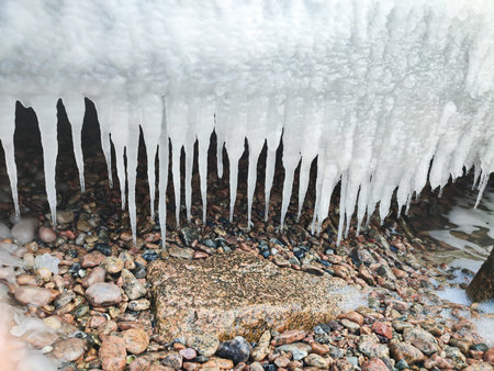 Winter frozen icicles hanging from rock on sea coast