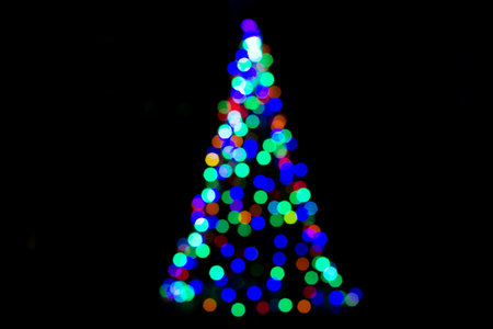 Christmas tree with colorful defocused lights glowing outdoor at night