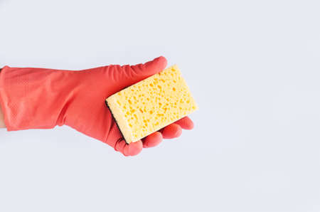Hand in rubber glove holding yellow sponge. Cleaning service concept. Space for textの写真素材