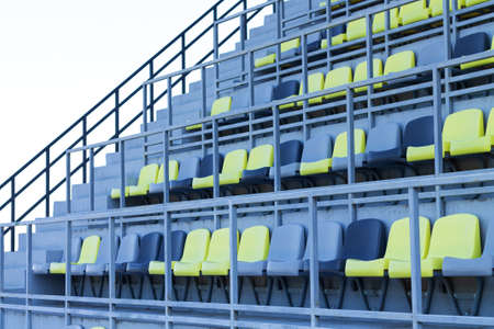 Vacant plastic gray and yellow seats or chairs at stadiumの写真素材