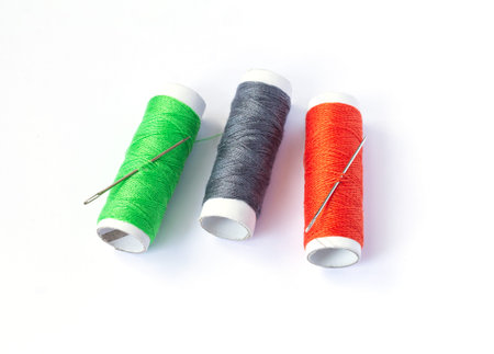 Three spools of sewing threads with needle, set of seamstress isolated on white background.の写真素材