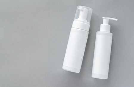 Mock-up of white plastic cosmetics bottles with skin care product on gray background. top viewの写真素材