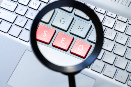 Magnifying glass and computer keyboard with text SEO on red keys