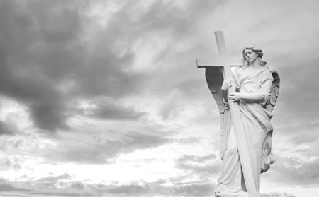 Black and white holy angel with wings holding large cross on sky backgroundの写真素材