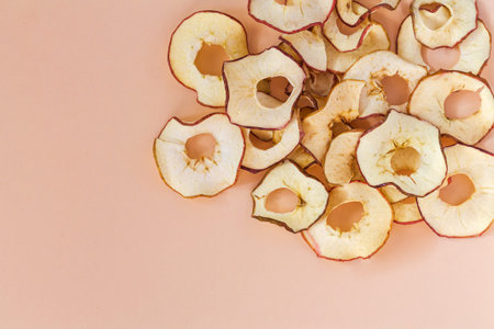 Heap of dried apple chips on kitchen table. Raw foodism and healthy vegan food concept