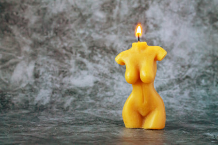 Organic beeswax candle shaped as female body on stone tableの写真素材