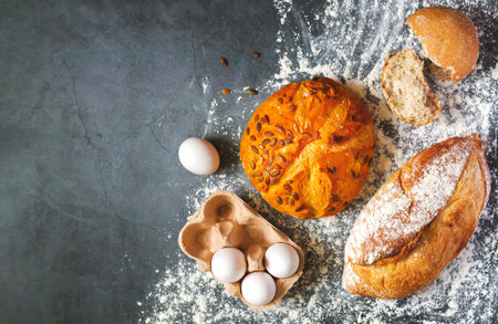 Bakery background with set of different freshly baked crispy bread and eggs on flour kitchen table