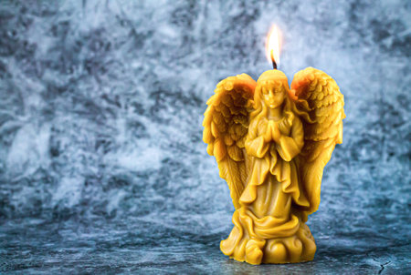 Beeswax praying angel candle on stone backgroundの写真素材