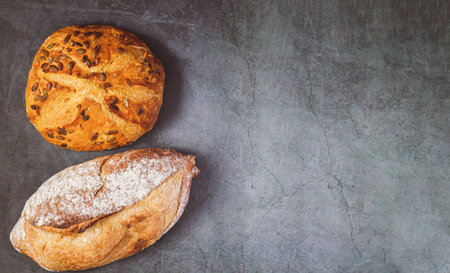 Bakery background with two different freshly baked crispy breads on kitchen tableの写真素材