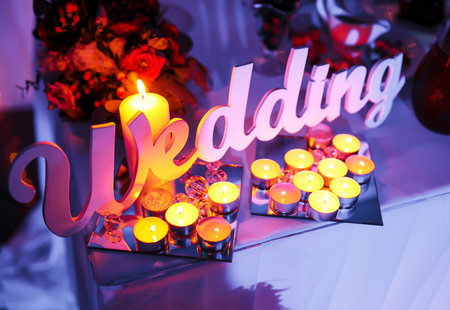 Word wedding, white wooden letters with candles on holiday table. wedding decor. Celebrating wed ceremony conceptの写真素材