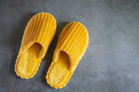 Home yellow slippers on a gray stone floorの写真素材