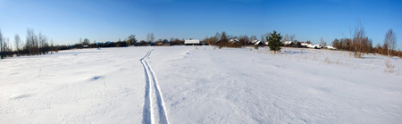 Ski tracks in the field behind the village on a Sunny winter's day.の写真素材