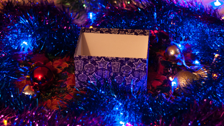 Empty Christmas box among the tinsel and glowing lights..の写真素材