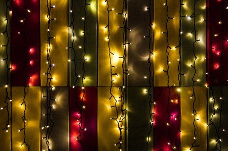 Christmas garlands glow in the dark on the background of colorful wallの写真素材