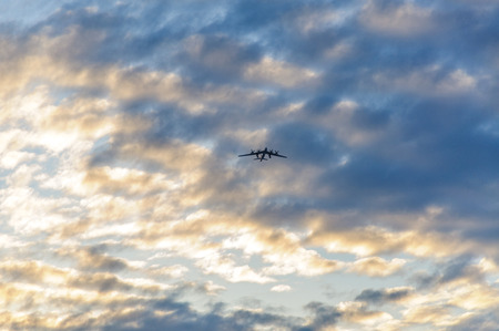 Silhouette of the plane in the clouds at sunsetの写真素材