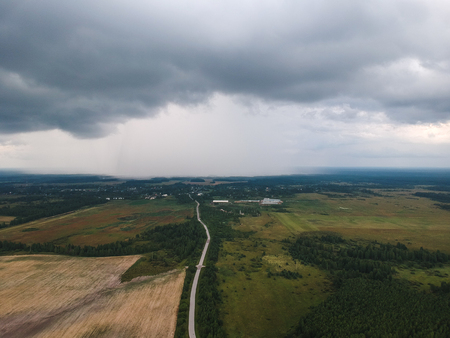view of the road to a huge cloud with rain from the height of the quadrocopter, around the road forests and fields. Way to trouble.の写真素材