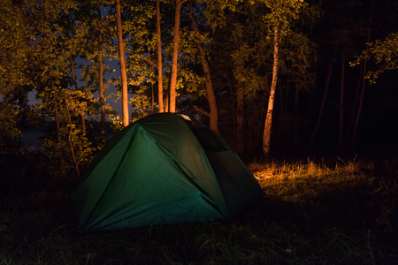 Green tent by the fire in the summer forestの写真素材