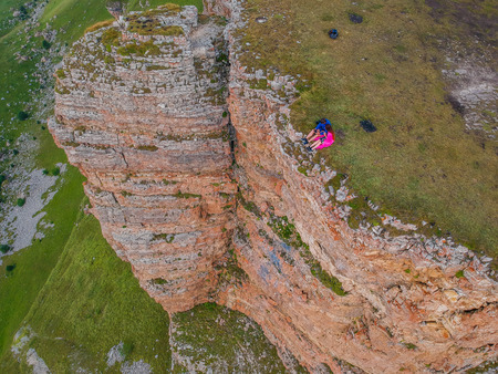 Couple in love sitting on a cliff of a mountain plateau, the view from the quadrocopterの写真素材