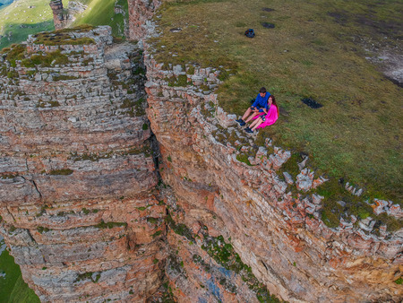 Couple in love sitting on a cliff of a mountain plateau, the view from the quadrocopterの写真素材