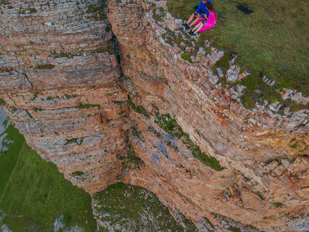 Couple in love sitting on a cliff of a mountain plateau, the view from the quadrocopterの写真素材