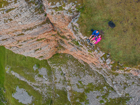 Couple in love sitting on a cliff of a mountain plateau, the view from the quadrocopterの写真素材