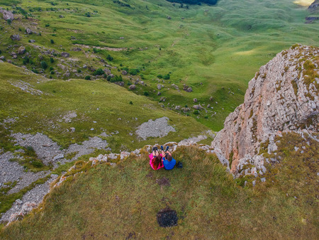 Couple in love sitting on a cliff of a mountain plateau, the view from the quadrocopterの写真素材