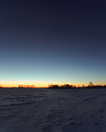 Winter, frosty morning in the village before dawn in the field.の写真素材