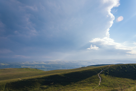 Mountain road stretching into the distance clouds on a summer day.の写真素材