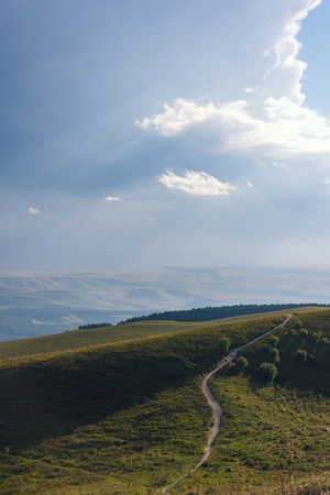 Mountain road stretching into the distance clouds on a summer day.の写真素材