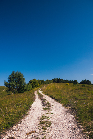 Mountain road stretching into the distance clouds on a summer day.の写真素材