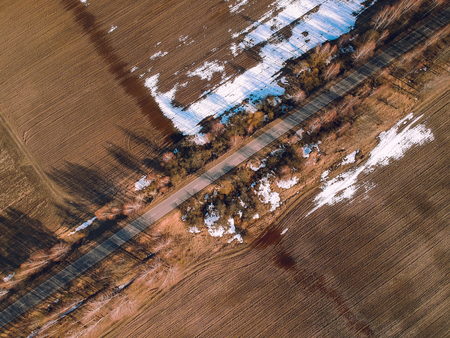 Spring road from a height, around the field and snowの写真素材