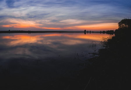 Large panorama of the most beautiful, scarlet sunset over the river in the springの写真素材