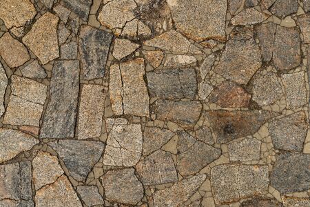 The texture of the sidewalk of chaotic granite stones of different colors with many cracksの写真素材