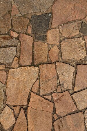 The texture of the sidewalk of chaotic granite stones of different colors with many cracksの写真素材