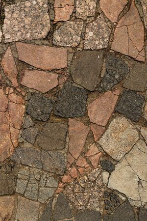 The texture of the sidewalk of chaotic granite stones of different colors with many cracksの写真素材